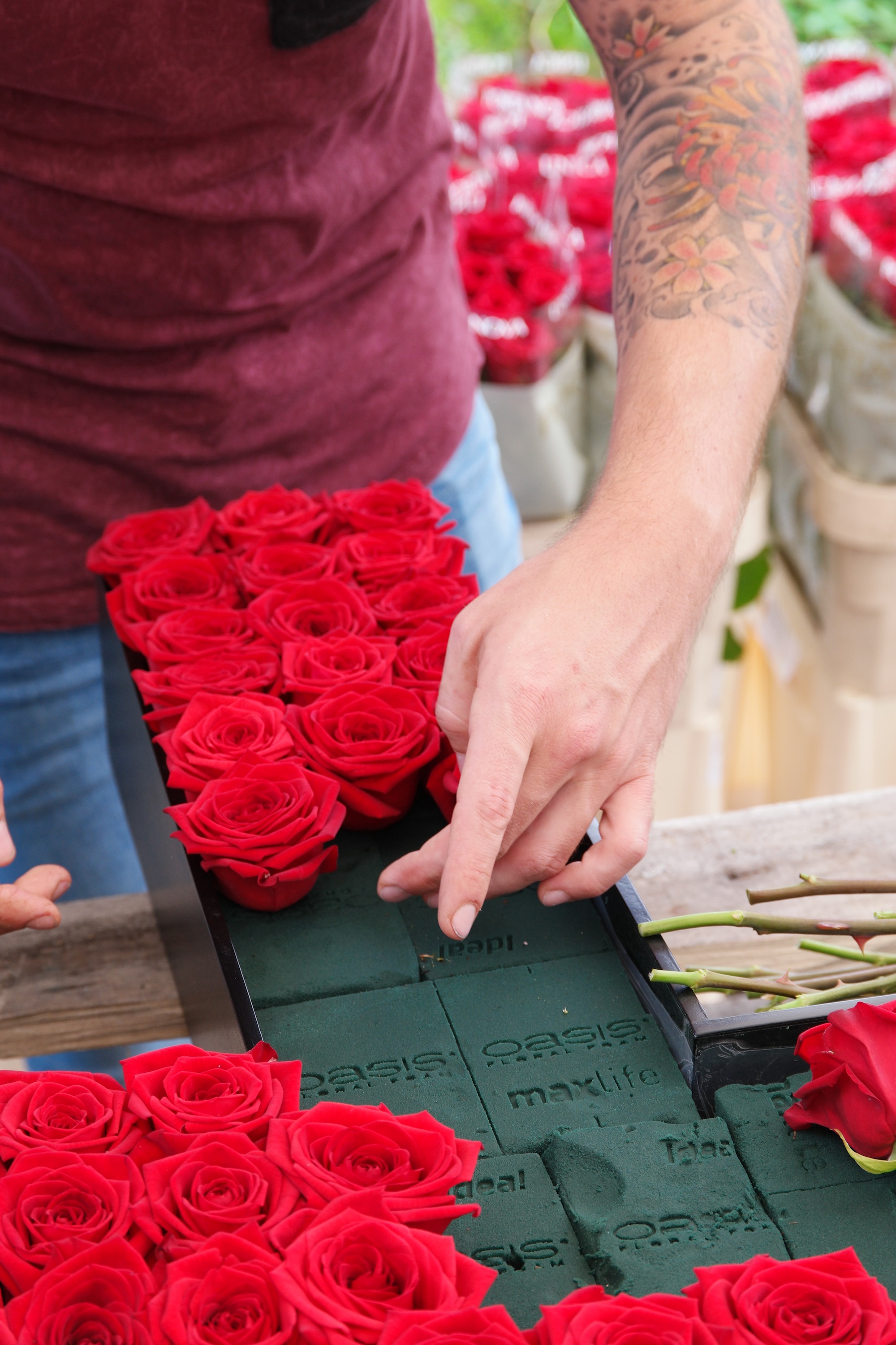 De Red Naomi rozen worden netjes gerangschikt op het frame van het kruis met behulp van Oasis steekschuim